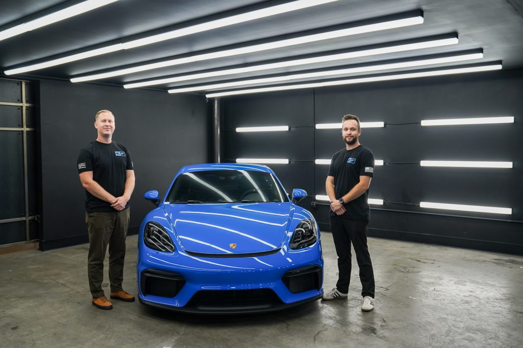team members standing next to a porsche
