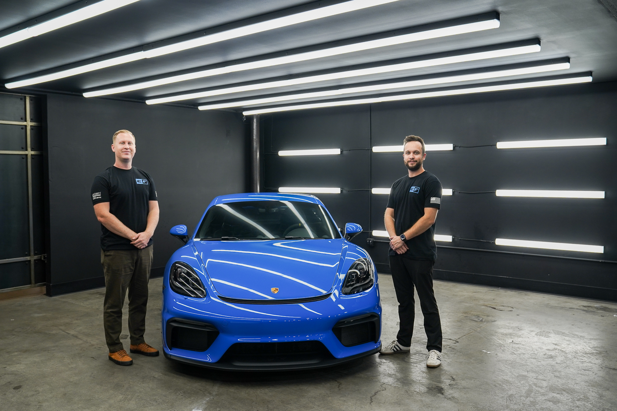 team members standing next to a porsche